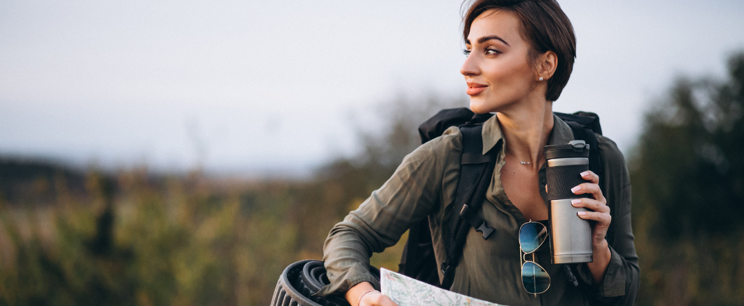 A Person Drinking From A To-Go Mug While Hiking