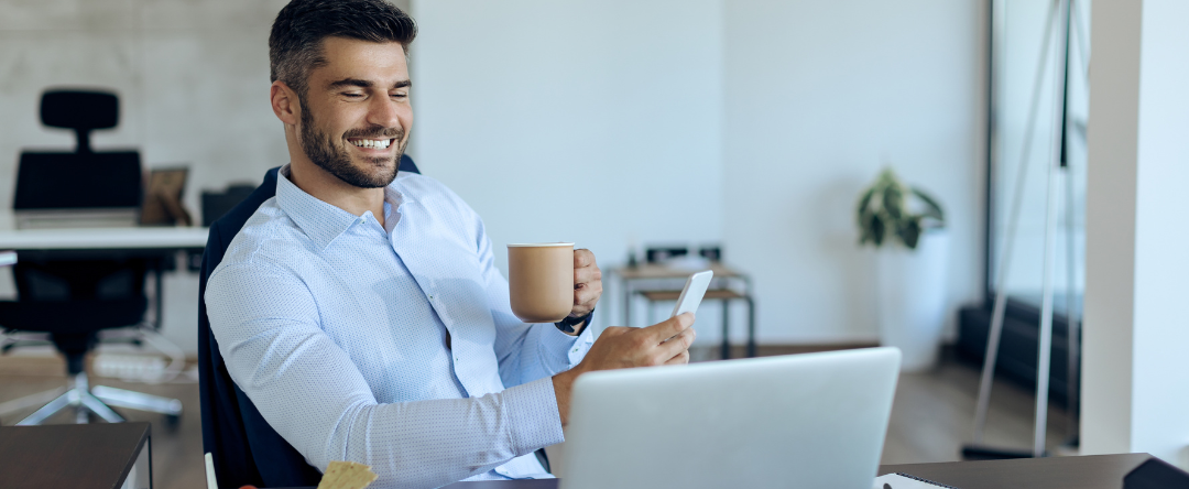 ​​​​A Man Enjoying A Cup Of Coffee And Reading About Magnesium For Brain Health On His Phone