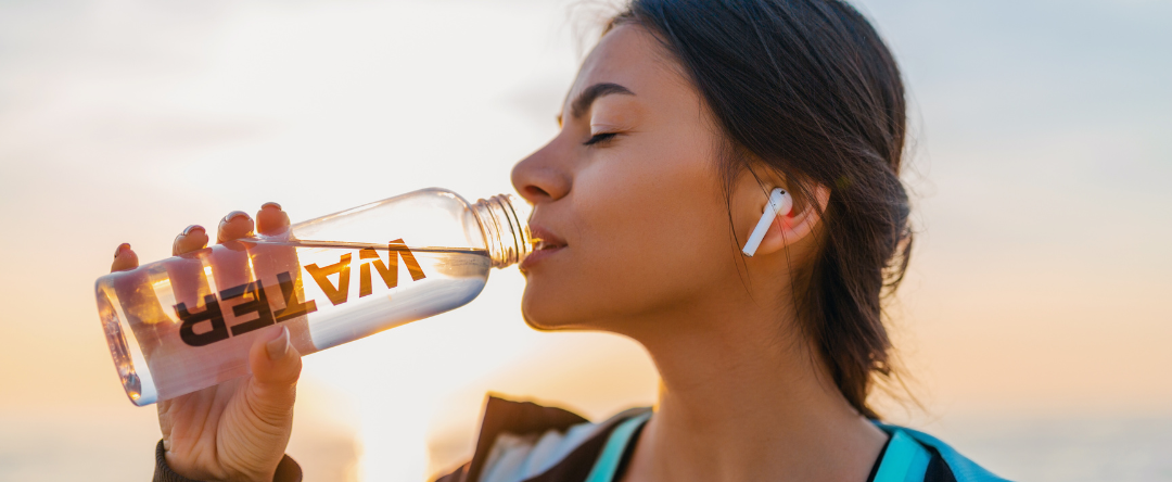 ​​​​A Woman Drinking Water With AirPods In